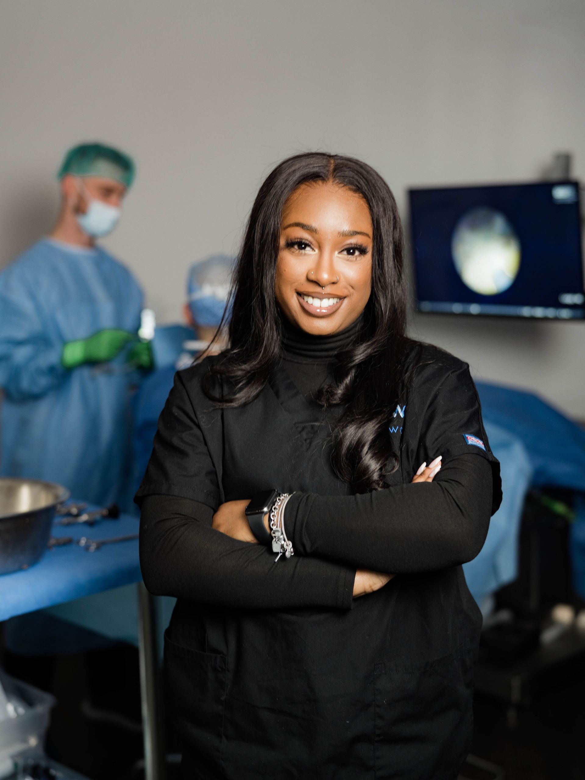 A woman is standing in a surgical room with her arms crossed.