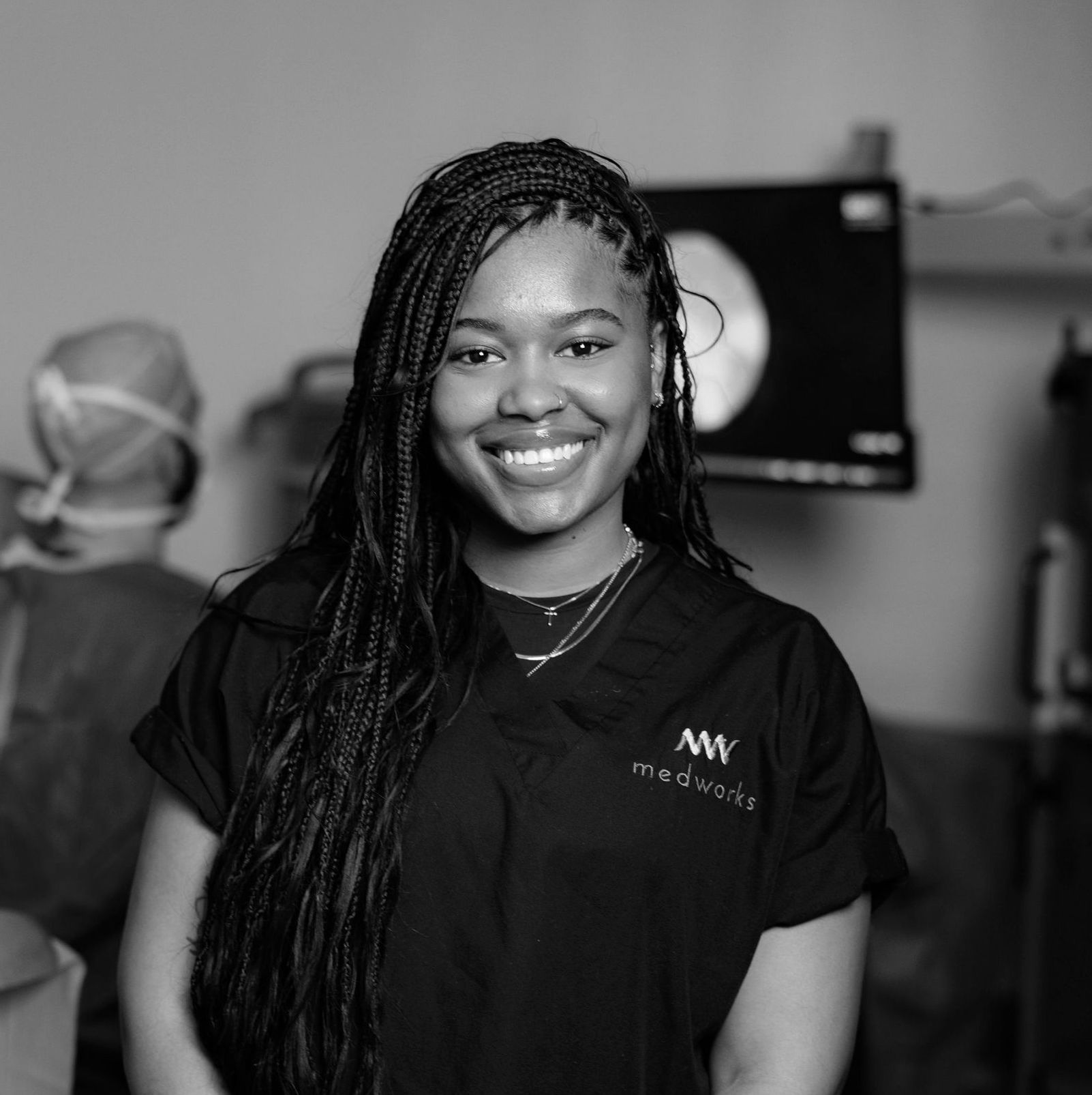 A black and white photo of a woman wearing a scrub that says mw medical