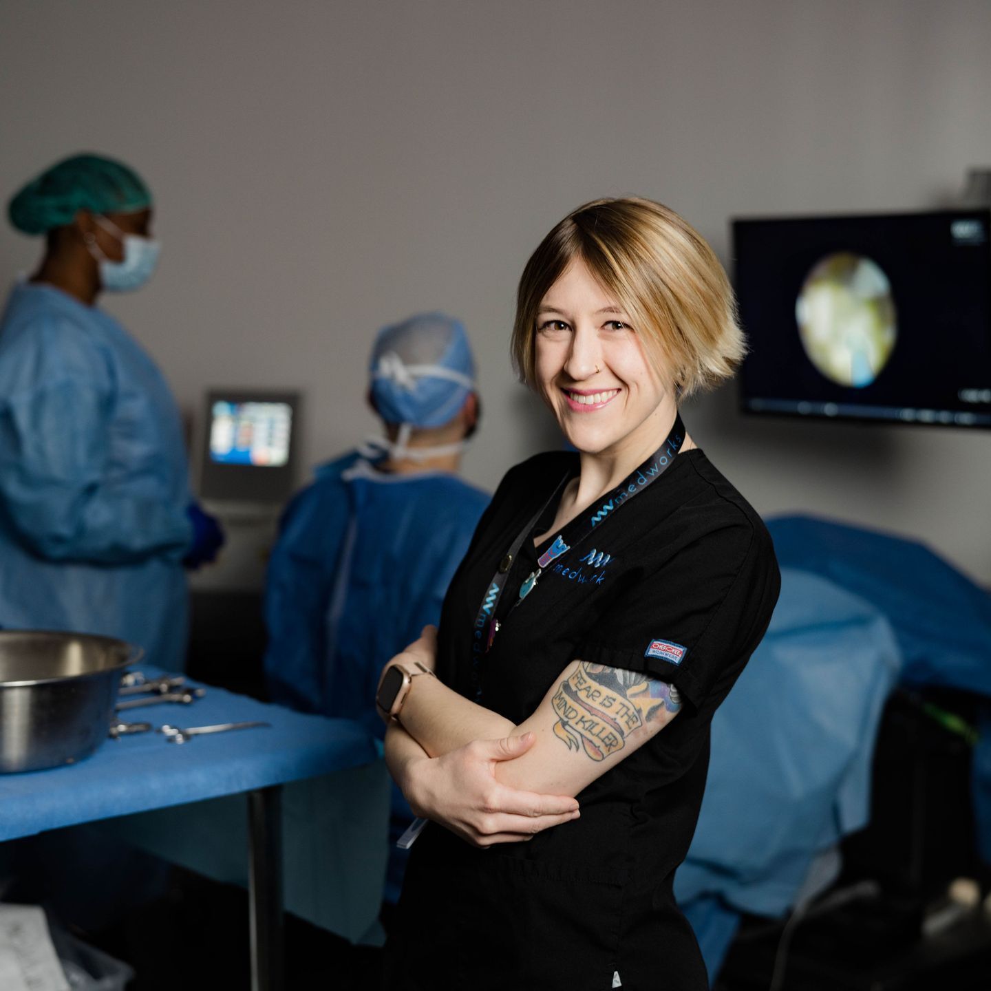 A woman with a tattoo on her arm is smiling in an operating room