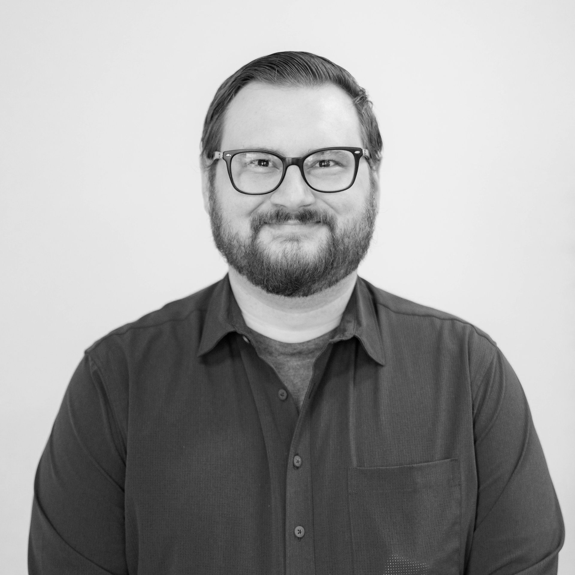 A man with a beard and glasses is wearing a black shirt.