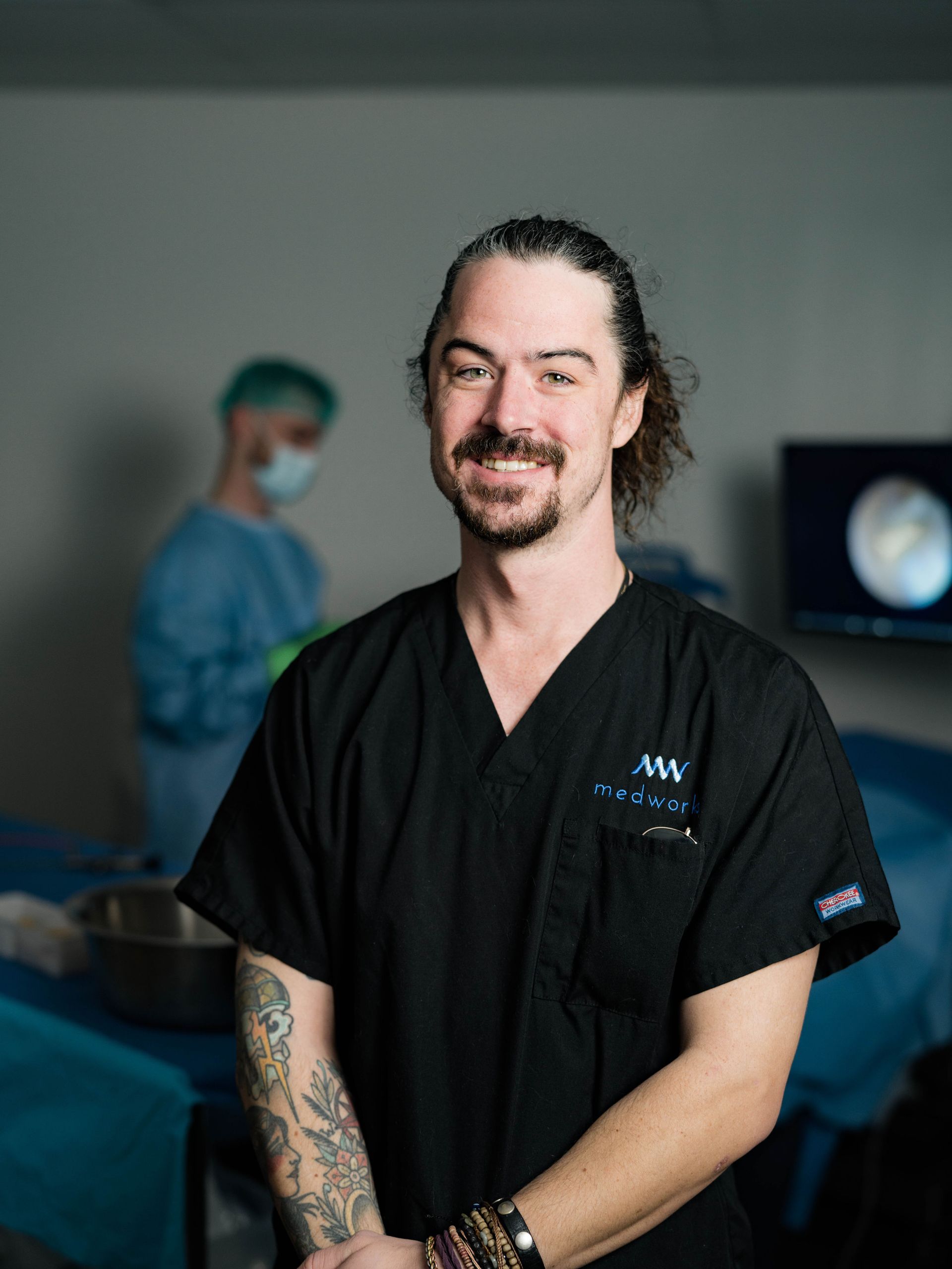 A man wearing a black scrub top with mw on it