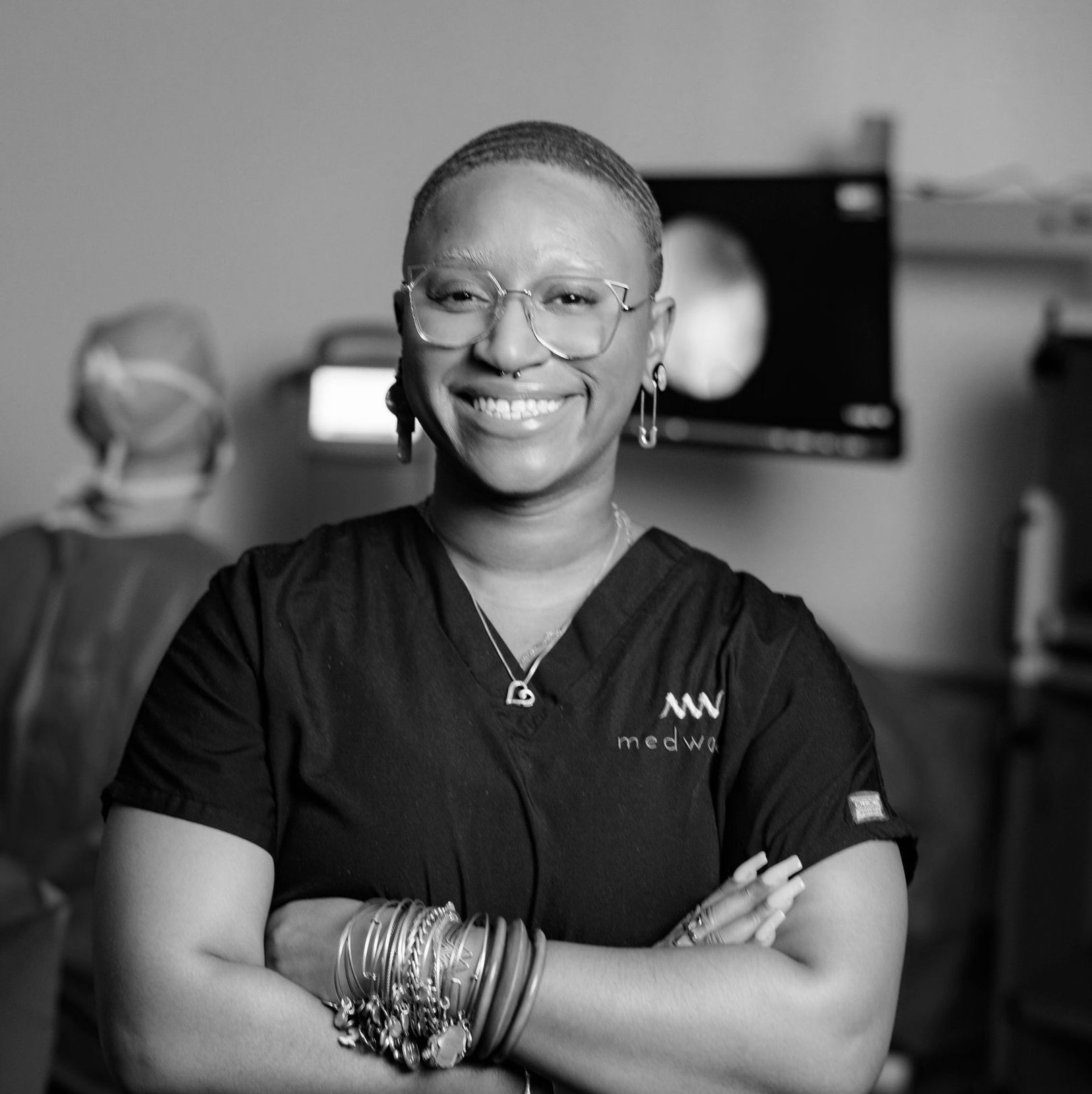 A black and white photo of a smiling woman wearing glasses