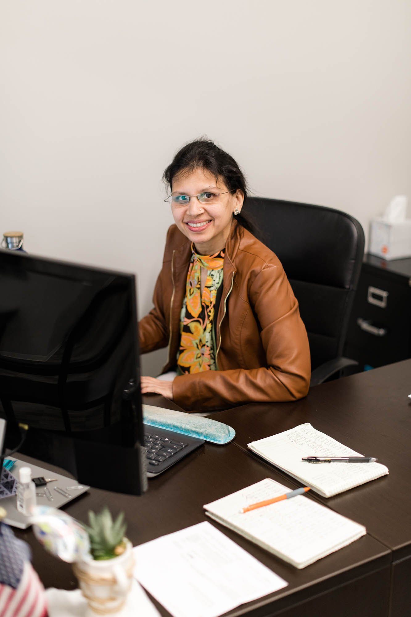 A woman is sitting at a desk in front of a computer.