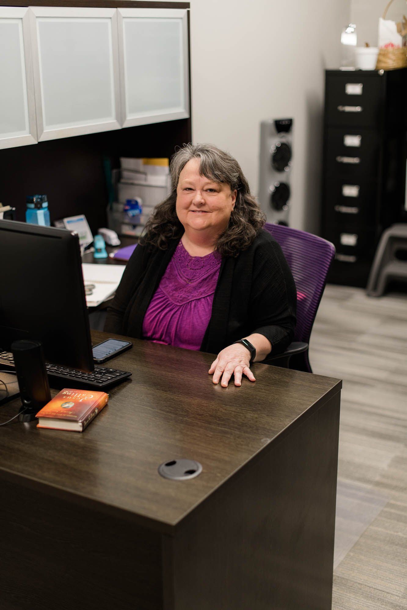 A woman is sitting at a desk in front of a computer.