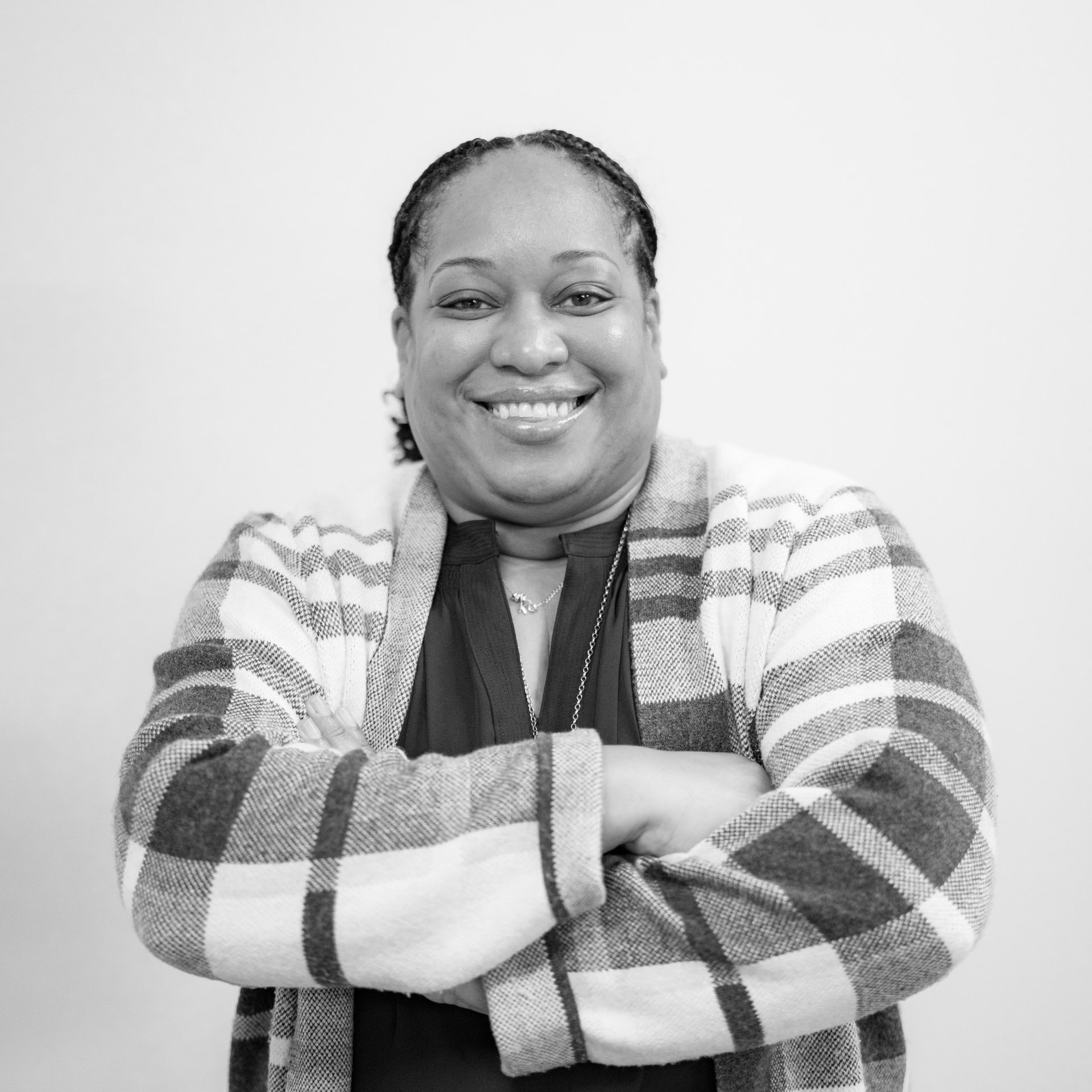 Smiling person with crossed arms wearing a striped jacket against a plain background