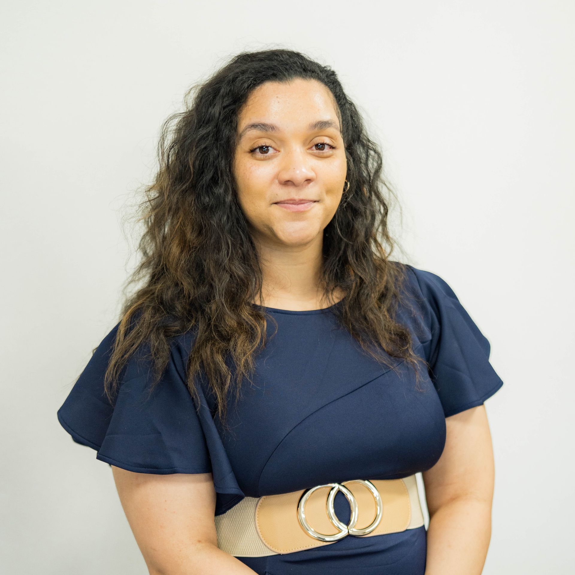 A woman in a black scrub top is smiling in an operating room.