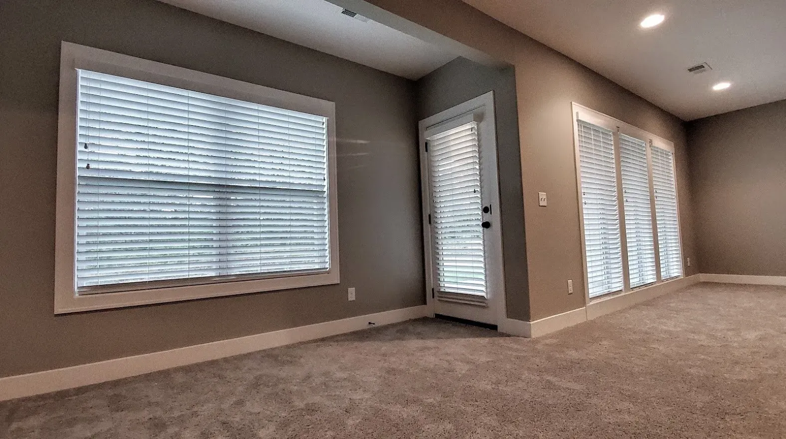 An empty room with a lot of windows and blinds.