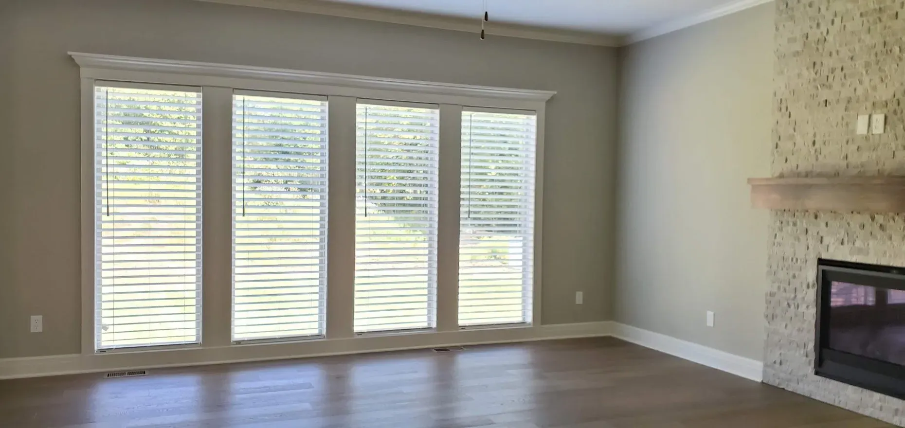 An empty living room with a fireplace and lots of windows.