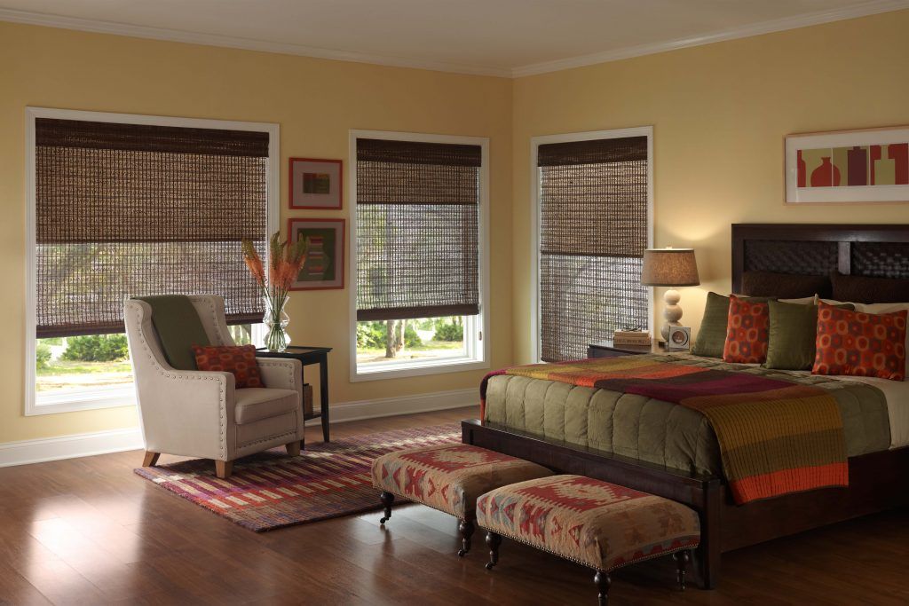 A bedroom with a bed , chair and ottomans