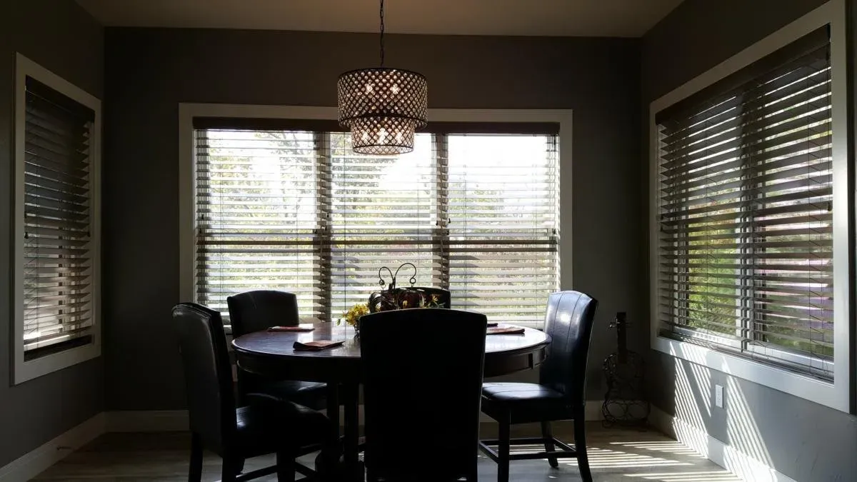 A dining room with a table and chairs and blinds on the windows