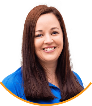 A woman with long brown hair is wearing a blue shirt and smiling.