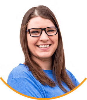 A woman wearing glasses and a blue shirt is smiling.