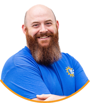 A man with a beard is wearing a blue shirt with a sun on it