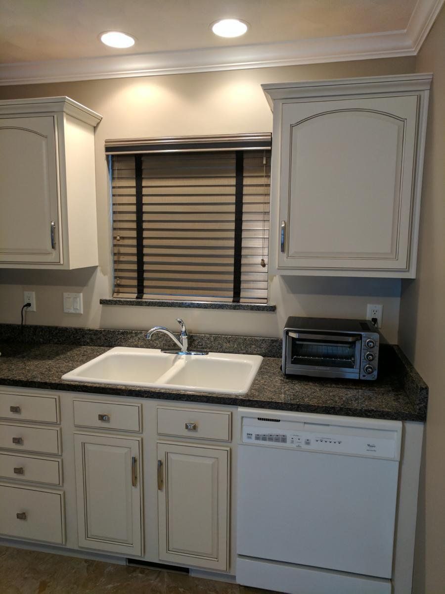 A kitchen with two sinks a microwave and a window