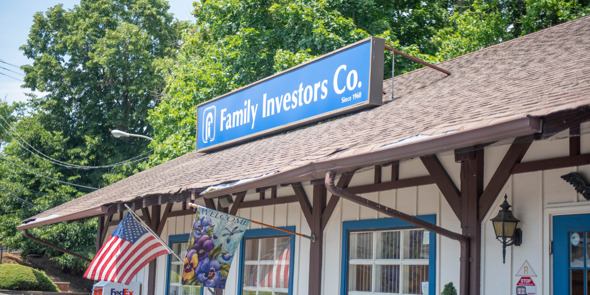 Storefront with a blue “Family Investors Co.” sign, wooden awning, and an American flag