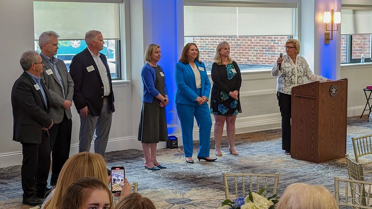 Family Investors Team standing on a stage at a formal event, with a podium and microphone in a banquet room.