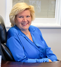 Darraugh Valli from Family Investors  blue blouse seated at a desk in an office
