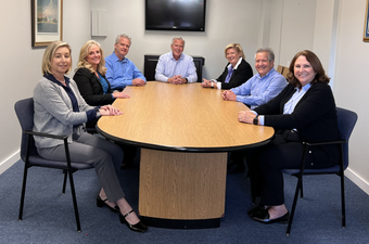 Familt Investors team around a conference table in a meeting room, smiling at the camera.