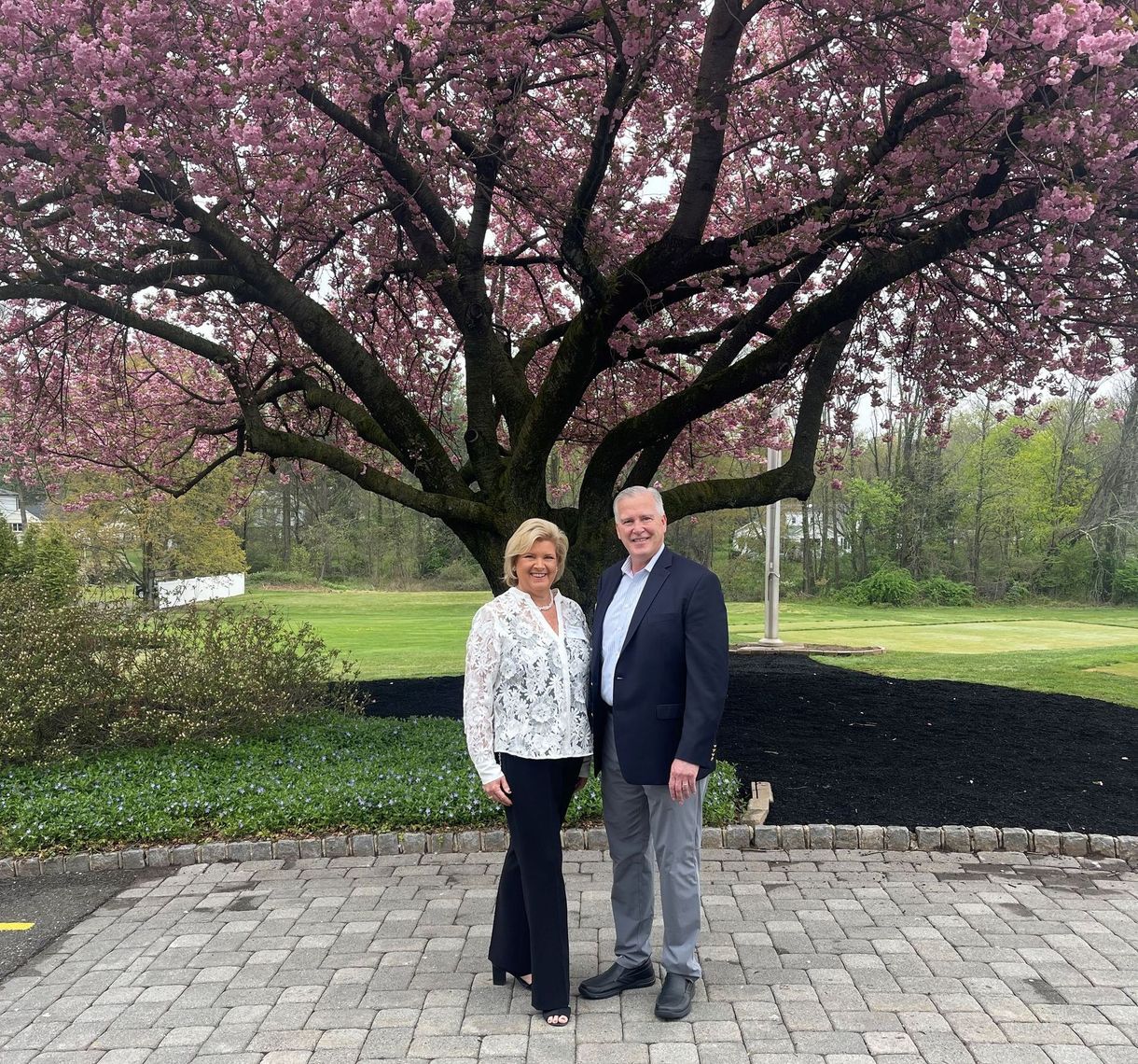 Pete Chemidlin and Darraugh Valli from Family Investors i standing on a paved path under a large pink-blossomed tree in a park