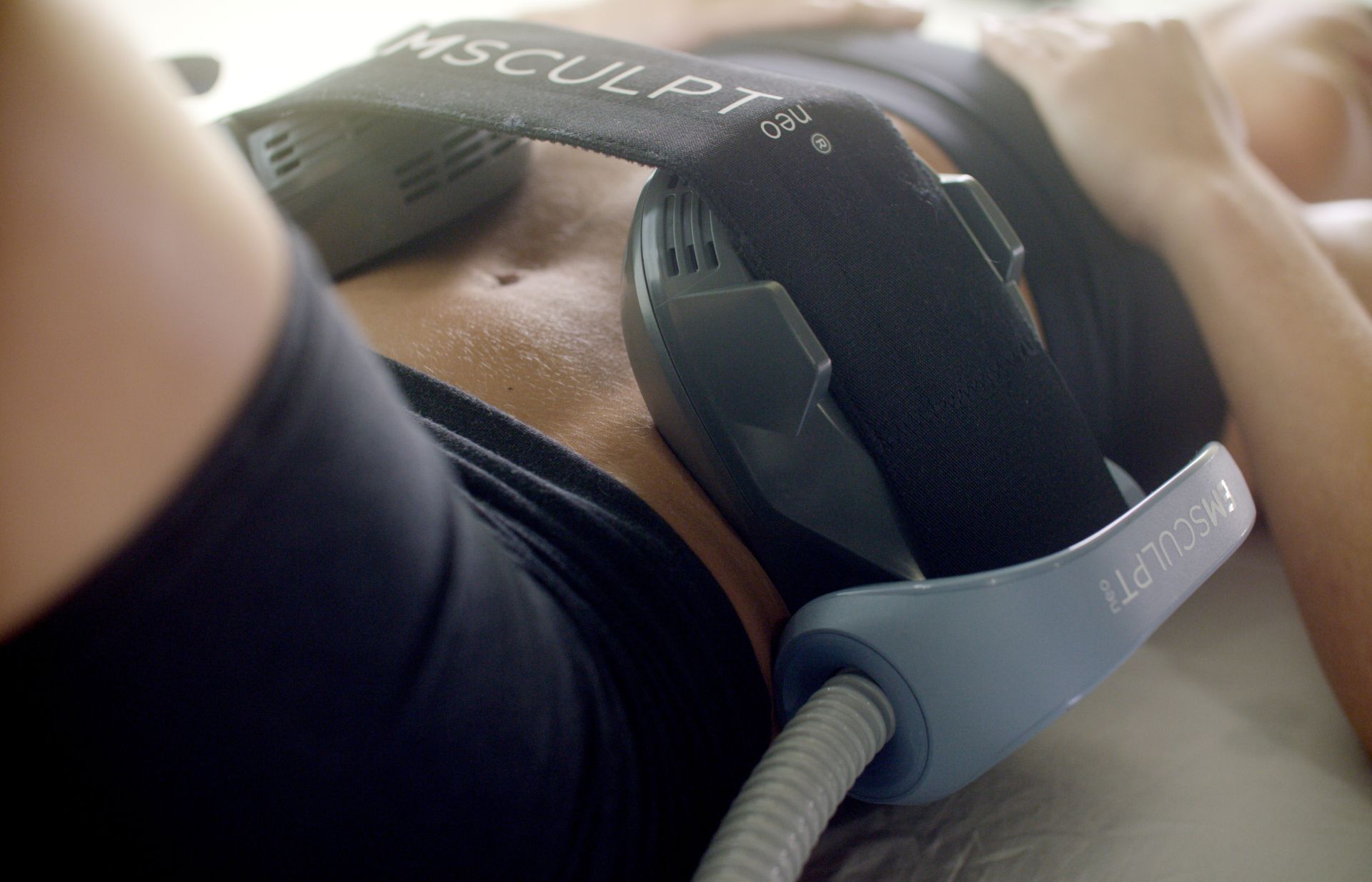 A woman is laying on a bed with a machine on her stomach.
