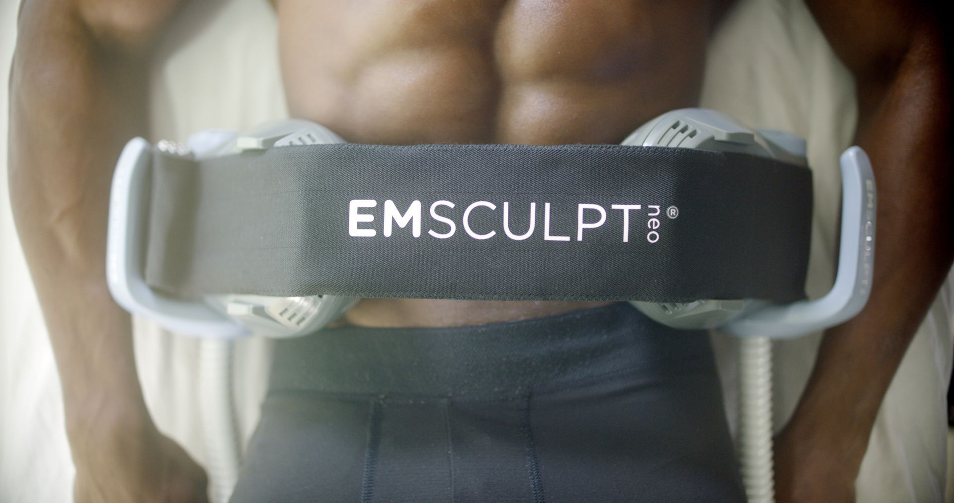 A man is laying on a bed with a belt around his waist.