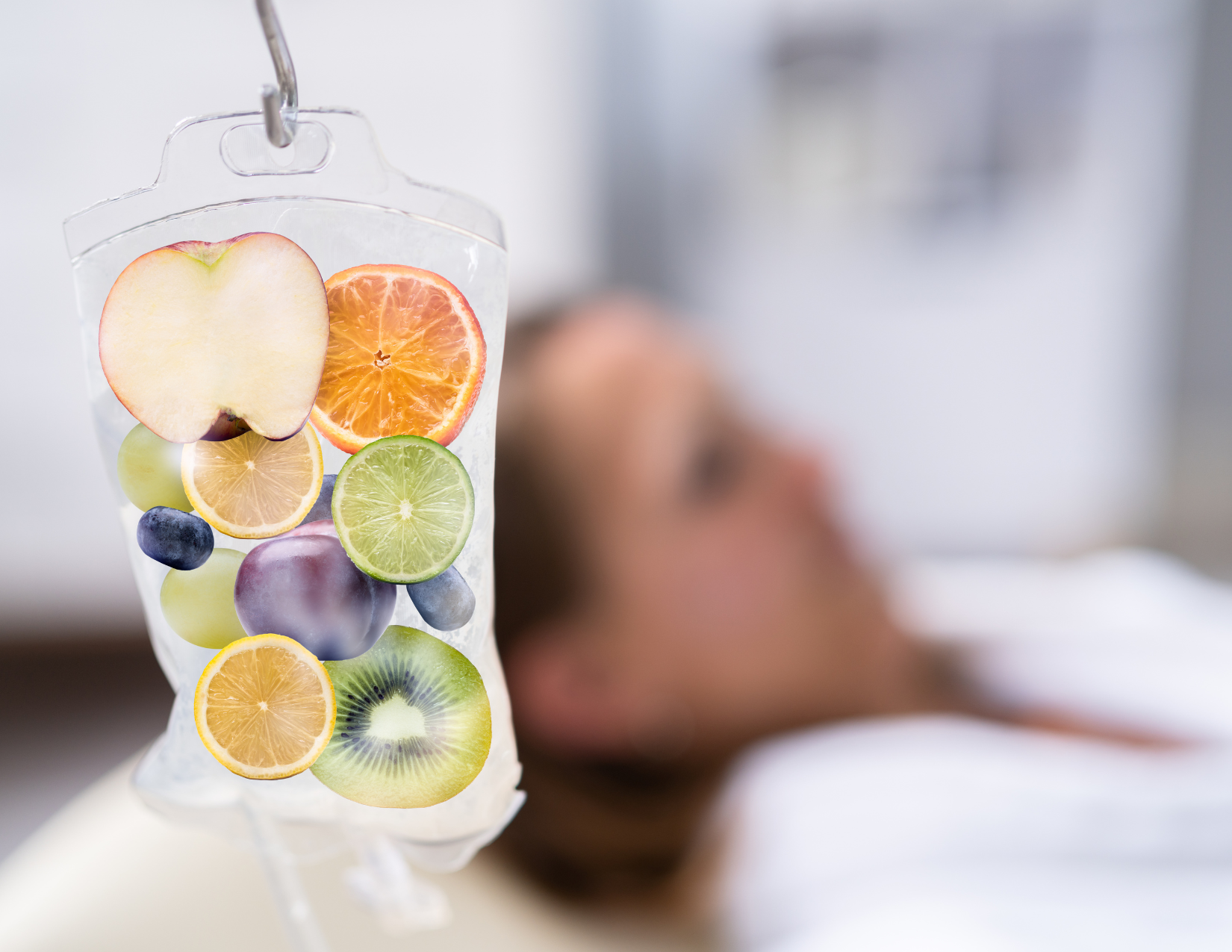 A woman is laying in a hospital bed with a bag of fruit hanging from a ceiling.