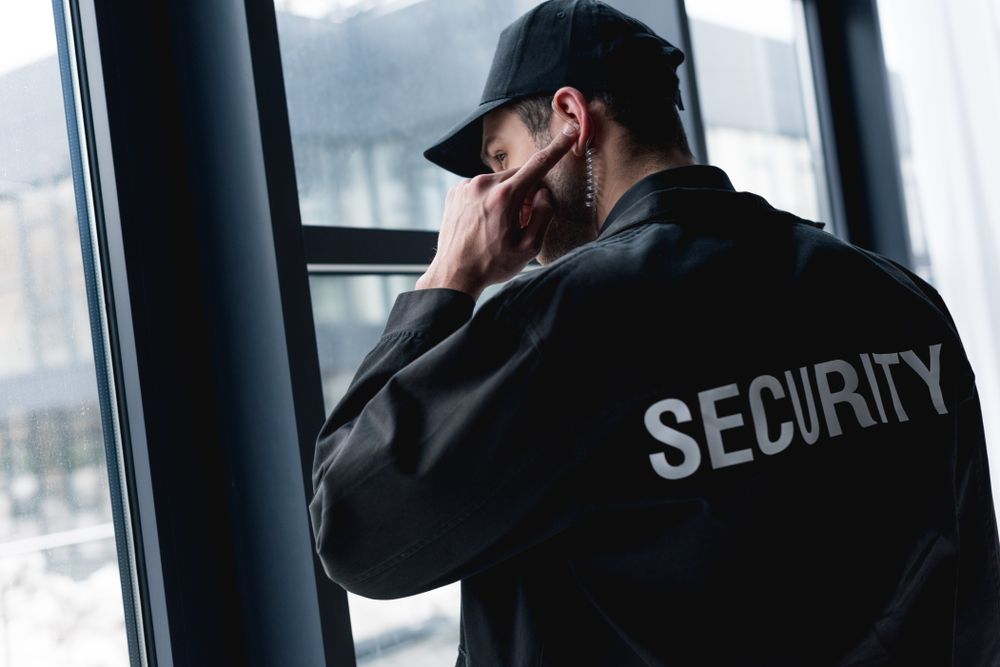 A Security Guard Is Looking Out Of A Window — Asset Security Group In Port Macquarie, NSW