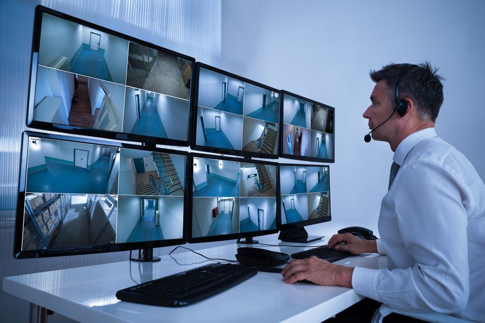 A Man is Sitting at a Desk Looking at a Bunch of Monitors — Asset Security Group In King Creek, NSW