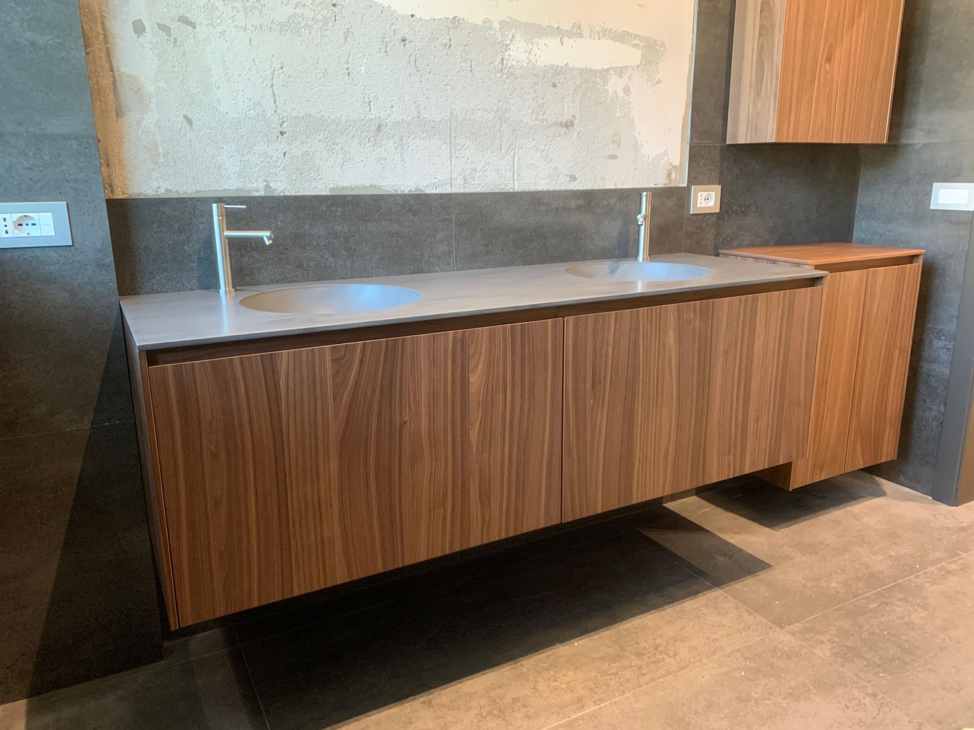 Un bagno con mobiletto in legno e due lavandini.