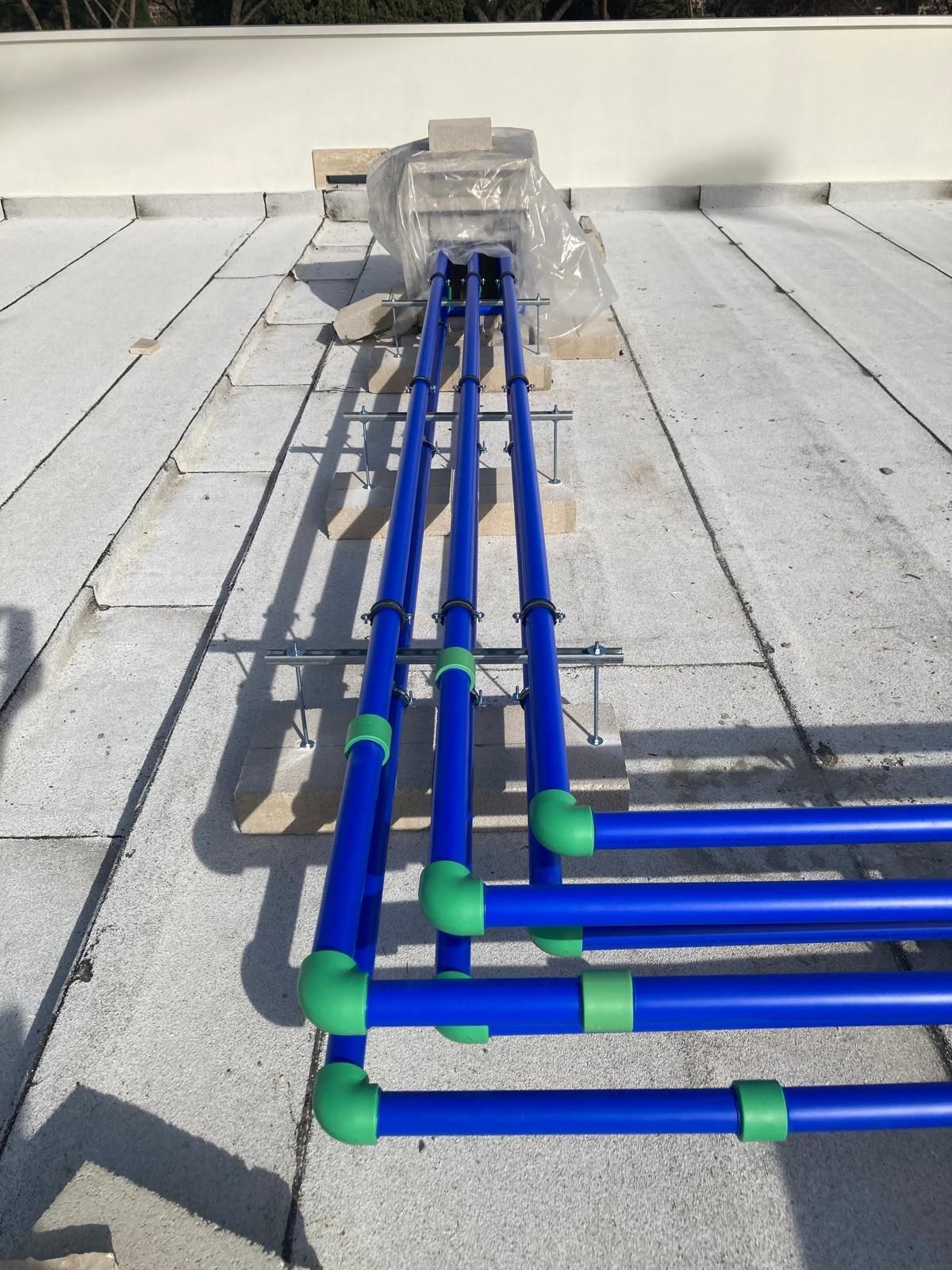 Una fila di tubi blu con raccordi verdi su un tetto