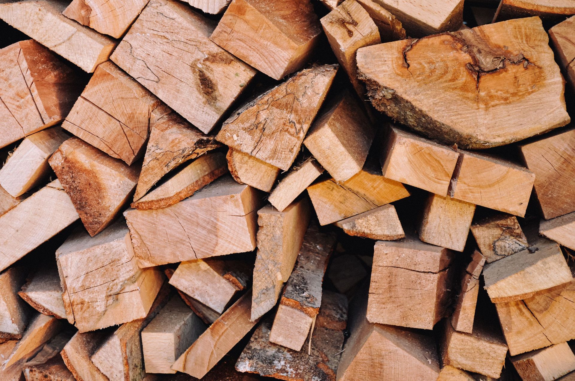 Stacked split firewood logs with rough bark and light brown cut surfaces