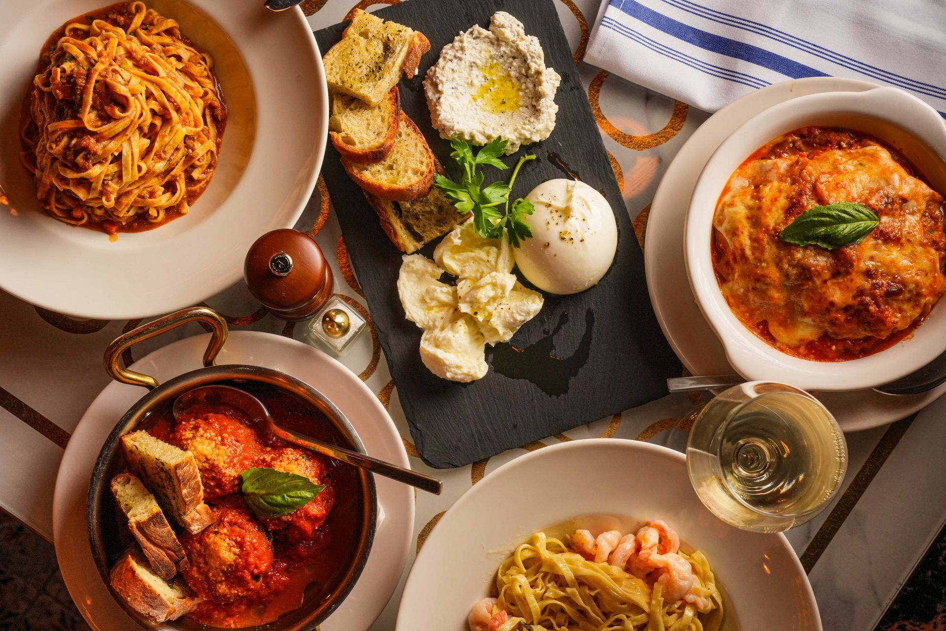 Italian dishes: pasta, meatballs, lasagna, cheese and dips on a table.