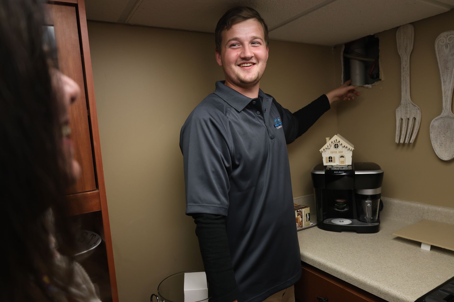 A man is standing in a kitchen pointing at something.