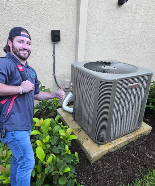 A man is standing next to a large air conditioner and giving a thumbs up.