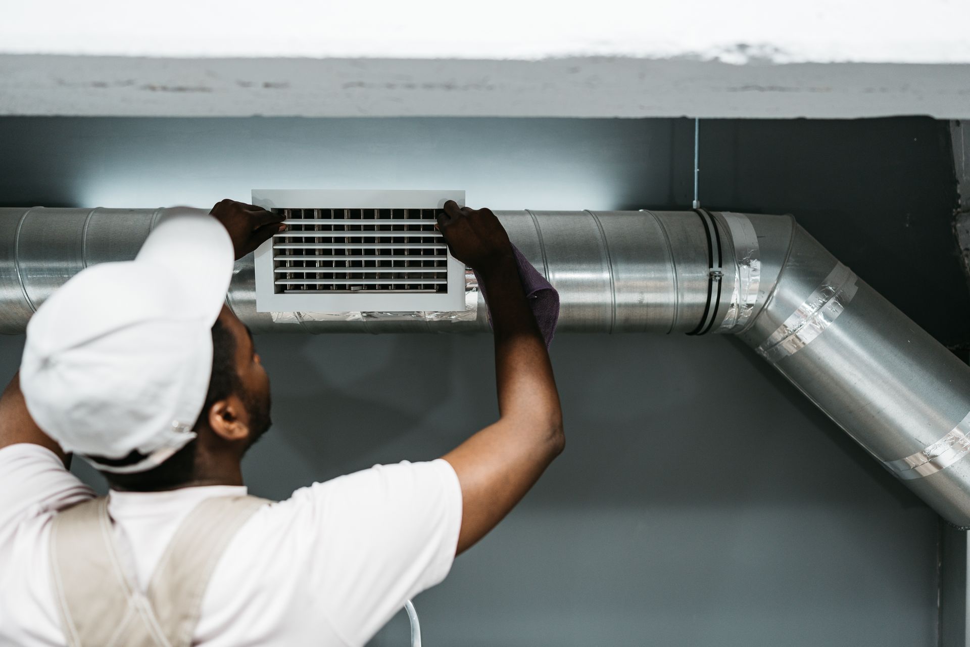 Person adjusting an air vent in a metal duct.