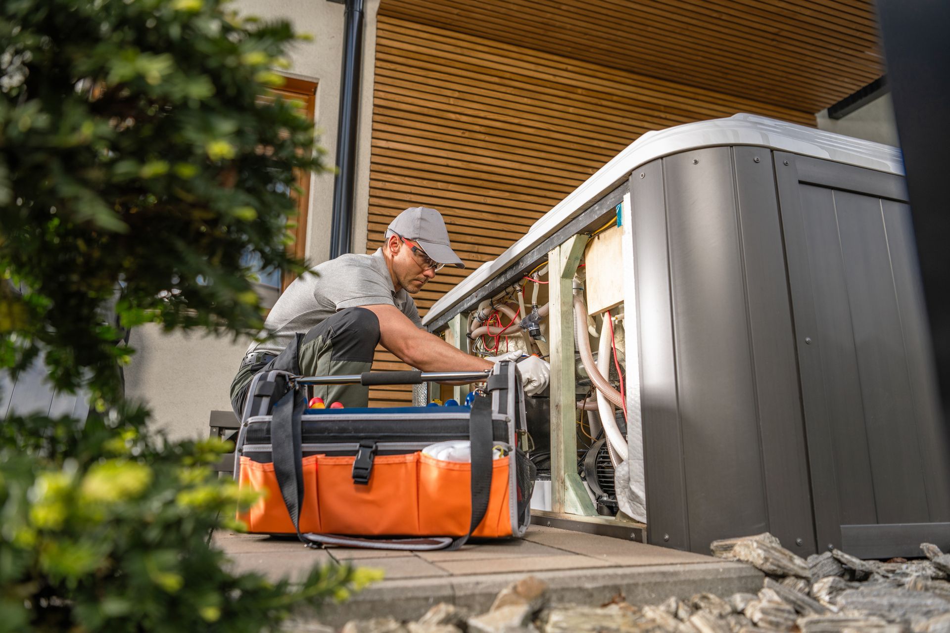 A technician working on machinery outdoors, orange toolbox in front.