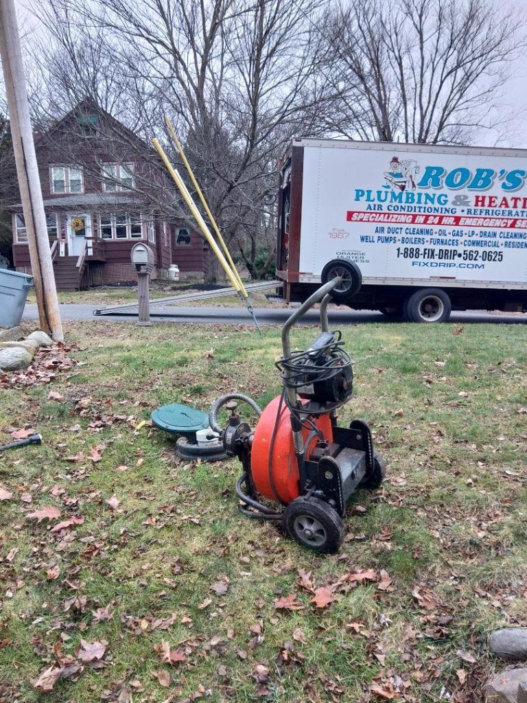 Plumbing truck and equipment on grass; near a house.