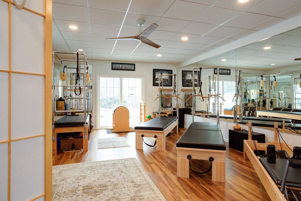 A pilates studio with a lot of equipment and a ceiling fan.