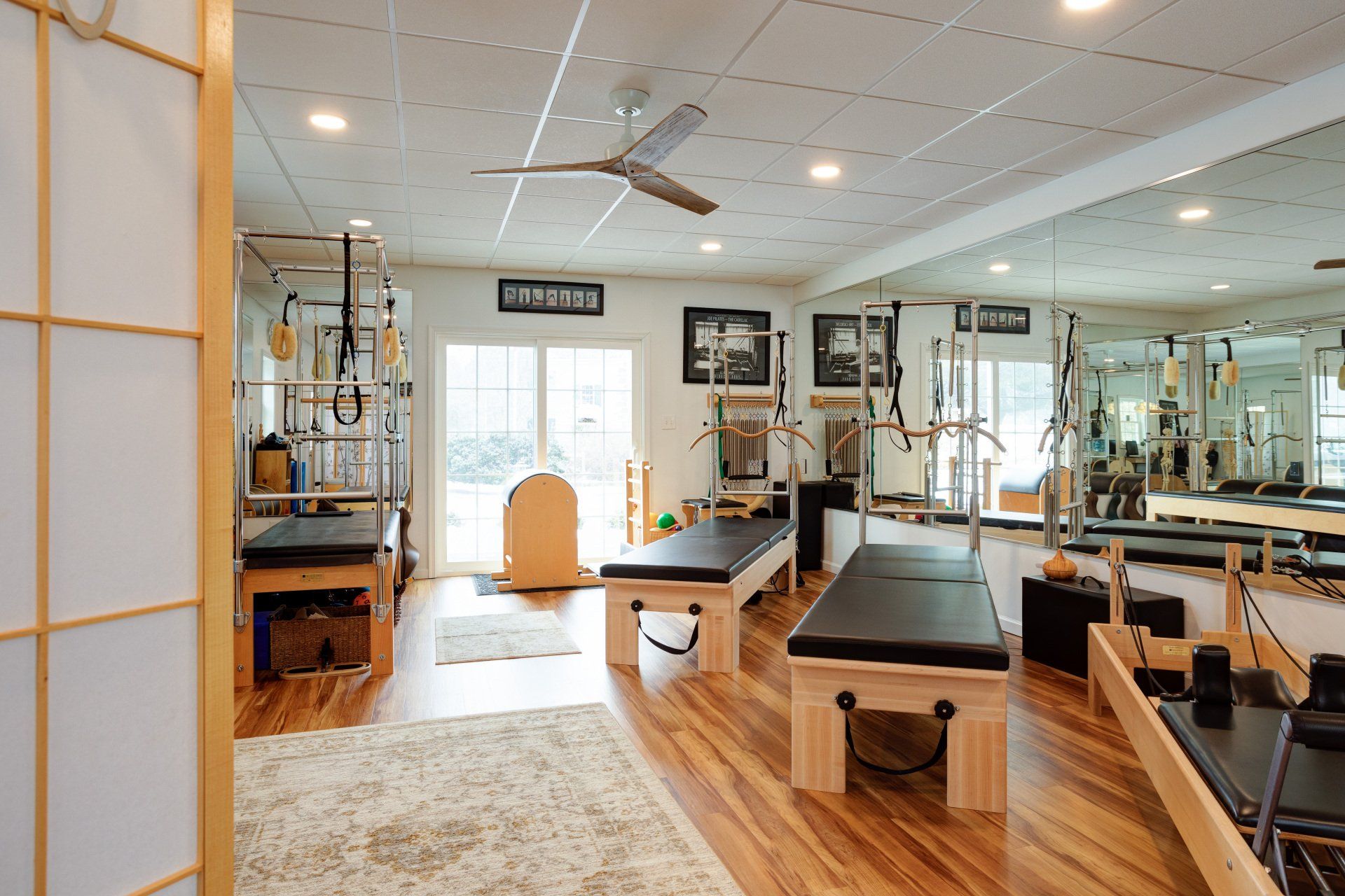 A pilates studio with a lot of equipment and a ceiling fan.