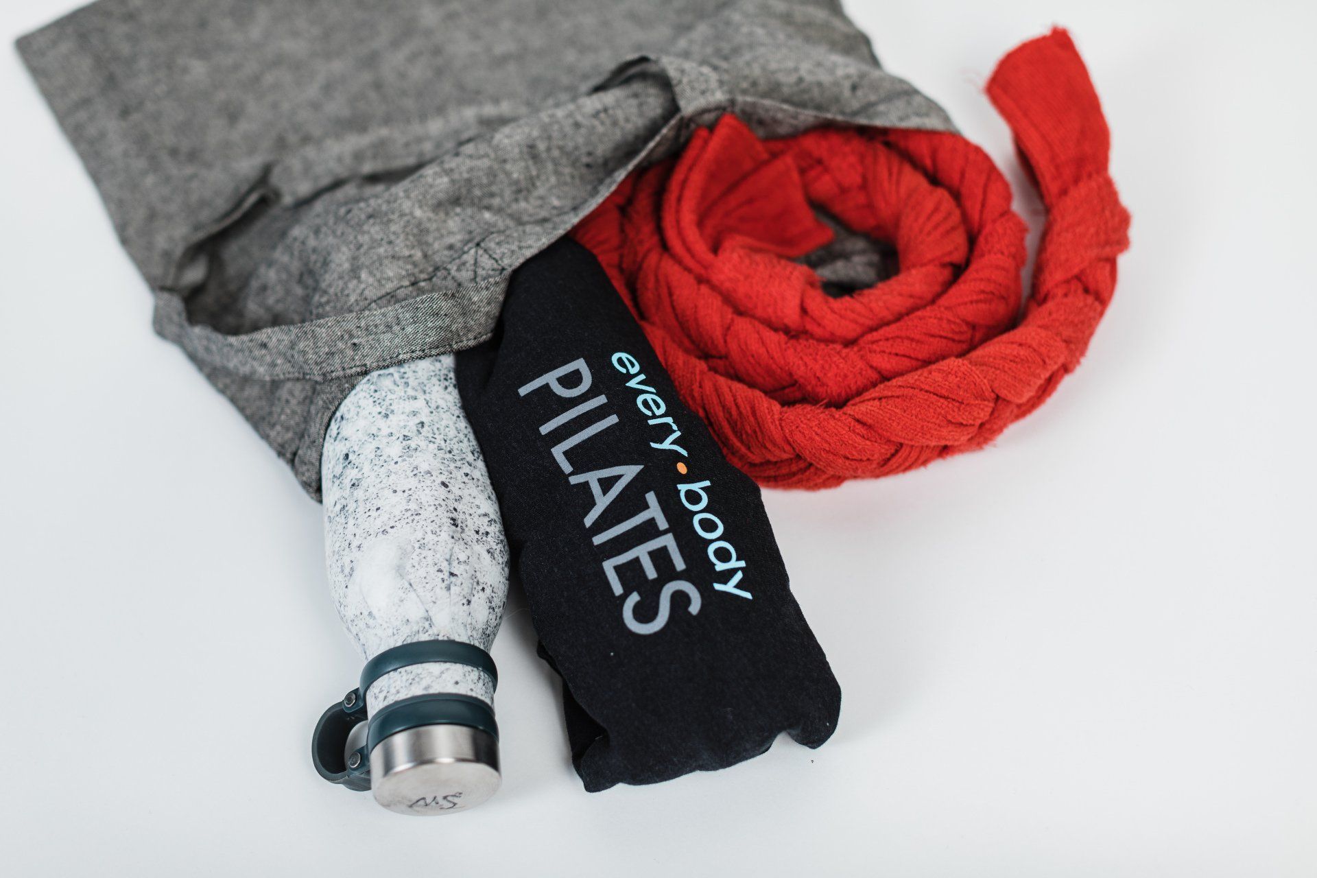 A bag of pilates items including a bottle and a scarf