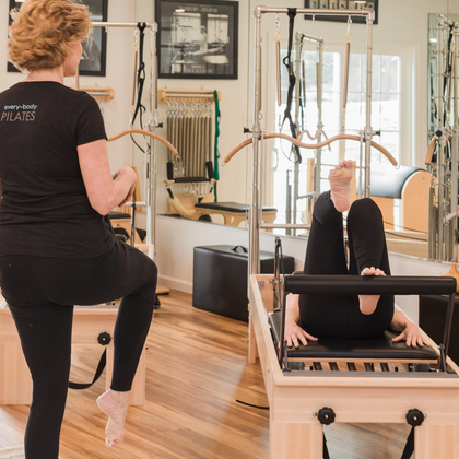 A woman in a black shirt with the word pilates on the back