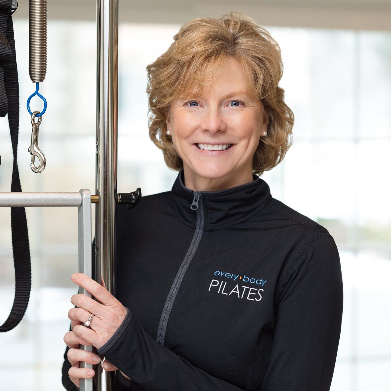 A woman wearing a black jacket that says pilates on it