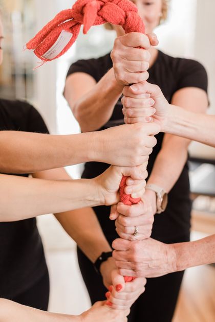 A group of people are holding a red rope in their hands.