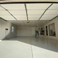 Empty white garage with an open door and a workbench against the right wall