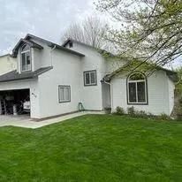 White two-story house with a garage and large green lawn under overcast skies