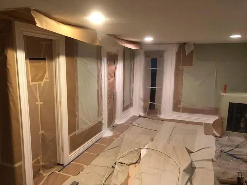 Living room with floors and furniture covered in plastic during home renovation