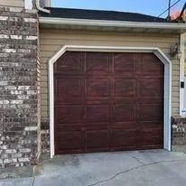 Closed dark brown garage door with white trim on a brick house exterior