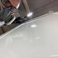 Person wearing a respirator mask inspecting a glossy white car surface in a workshop