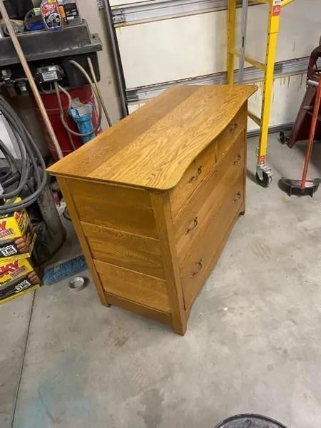 Wooden dresser with a glossy top in a garage workshop.
