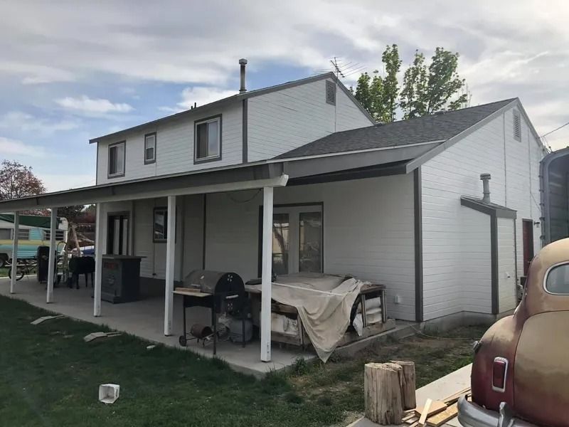 Two-story house with covered porch, outdoor furniture, and a parked car in the driveway